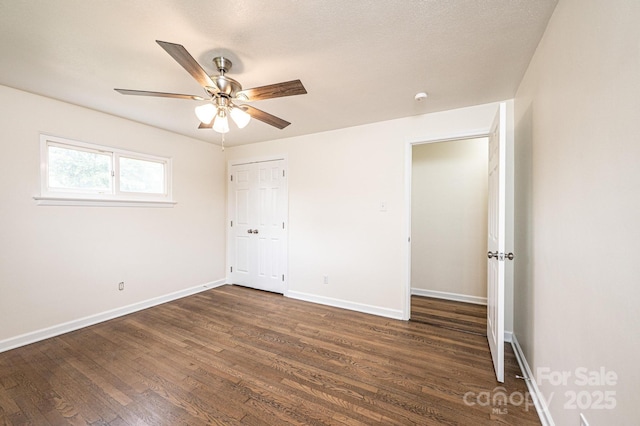 unfurnished bedroom featuring dark wood-style flooring, baseboards, a ceiling fan, and a closet