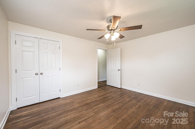 unfurnished bedroom with baseboards, a ceiling fan, a closet, and dark wood-type flooring