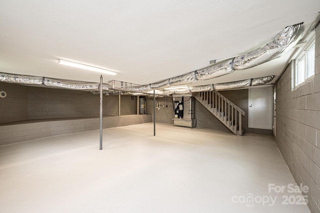 below grade area with heating unit, water heater, concrete block wall, and stairway
