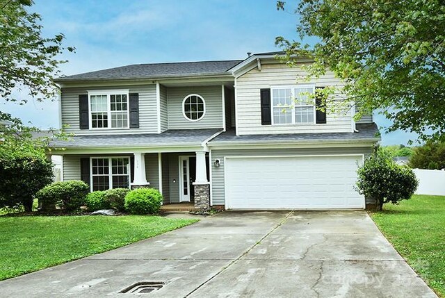 view of front of property with a front lawn, driveway, a garage, and covered porch
