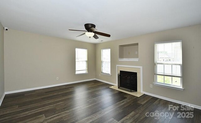 unfurnished living room featuring a fireplace with flush hearth, baseboards, a ceiling fan, and dark wood-type flooring