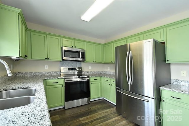 kitchen featuring light stone counters, green cabinetry, appliances with stainless steel finishes, dark wood-style flooring, and a sink