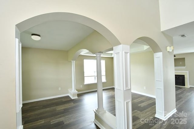 interior space featuring decorative columns, wood finished floors, visible vents, and baseboards