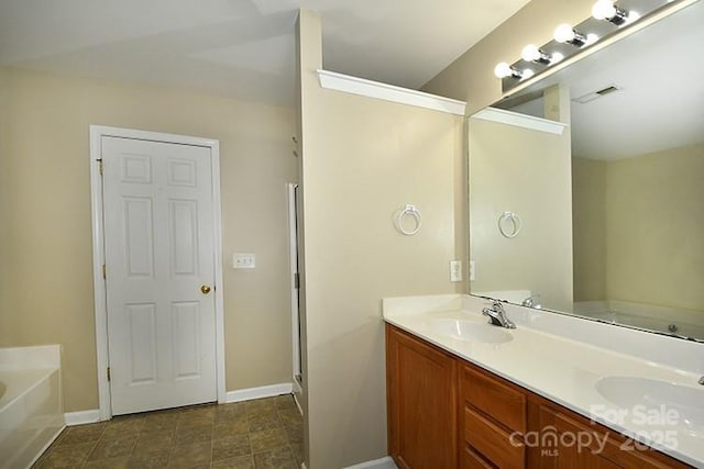 bathroom with a sink, a bath, double vanity, baseboards, and visible vents