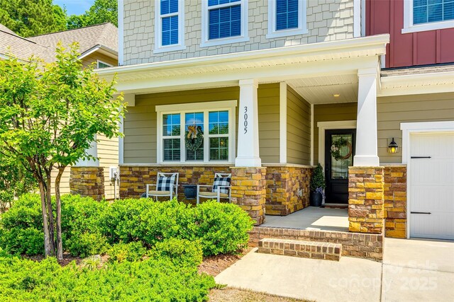 entrance to property with board and batten siding, a porch, and stone siding