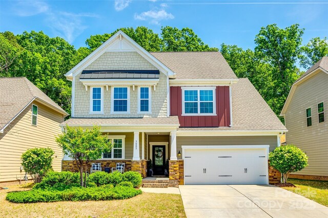 craftsman house with board and batten siding, a porch, driveway, and roof with shingles