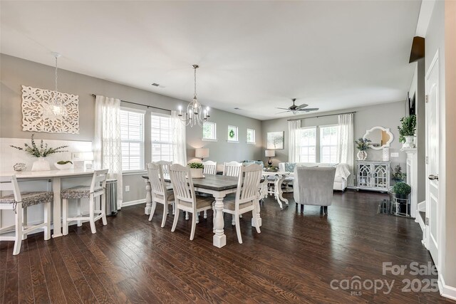 dining area with baseboards, dark wood finished floors, visible vents, and ceiling fan with notable chandelier