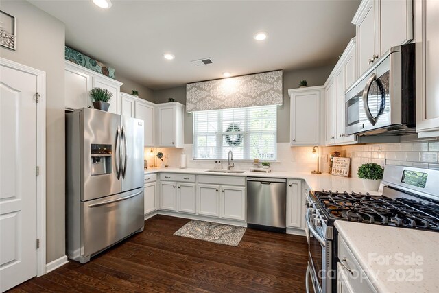 kitchen featuring a sink, white cabinetry, decorative backsplash, and stainless steel appliances