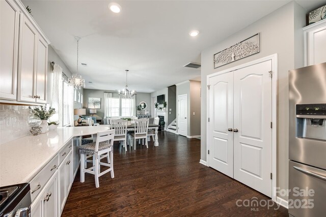 kitchen featuring dark wood-style flooring, visible vents, tasteful backsplash, white cabinets, and stainless steel appliances