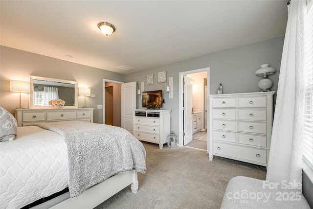 bedroom featuring multiple windows, ensuite bath, visible vents, and light colored carpet