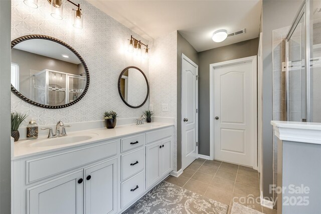 bathroom with double vanity, tile patterned floors, a sink, and a stall shower