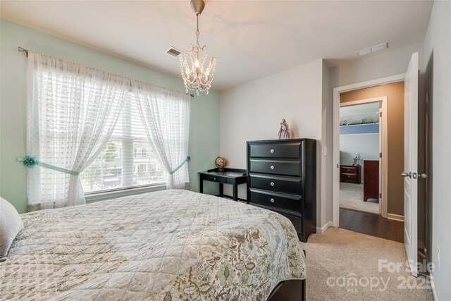 carpeted bedroom featuring baseboards, a chandelier, and visible vents