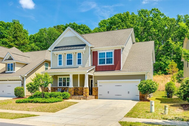 craftsman-style house with a shingled roof, stone siding, board and batten siding, a porch, and driveway
