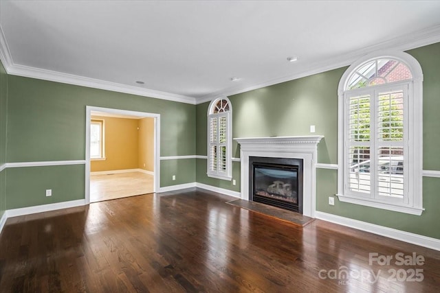 unfurnished living room with plenty of natural light, wood finished floors, a glass covered fireplace, and ornamental molding