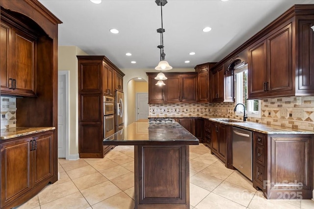kitchen with stainless steel appliances, tasteful backsplash, a sink, dark stone counters, and arched walkways
