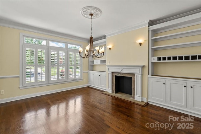 unfurnished living room with a chandelier, crown molding, dark wood finished floors, plenty of natural light, and baseboards