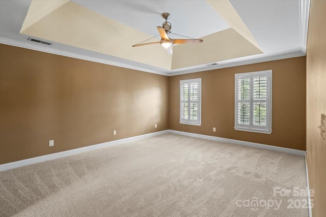 unfurnished room with a raised ceiling, carpet flooring, baseboards, ornamental molding, and ceiling fan