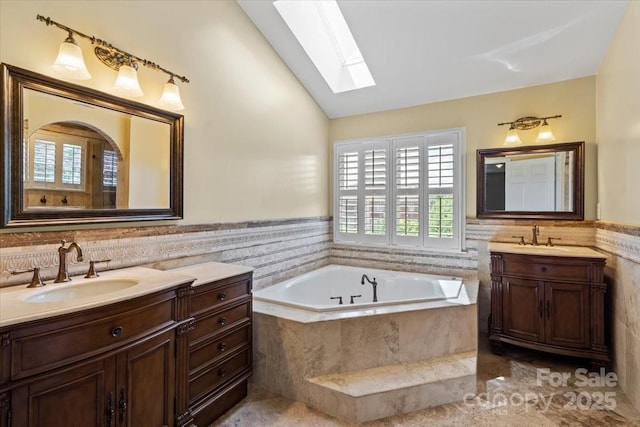 bathroom featuring a skylight, plenty of natural light, vaulted ceiling, two vanities, and a bath