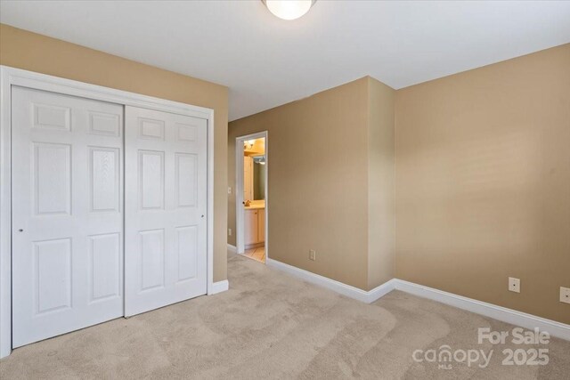 unfurnished bedroom featuring carpet, baseboards, and a closet