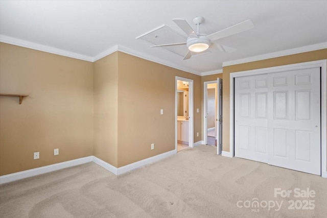 unfurnished bedroom with ornamental molding, carpet, baseboards, a closet, and ensuite bath
