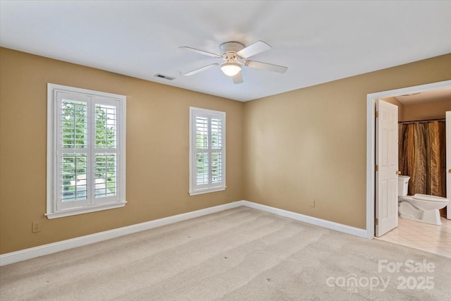 empty room with ceiling fan, baseboards, and light carpet