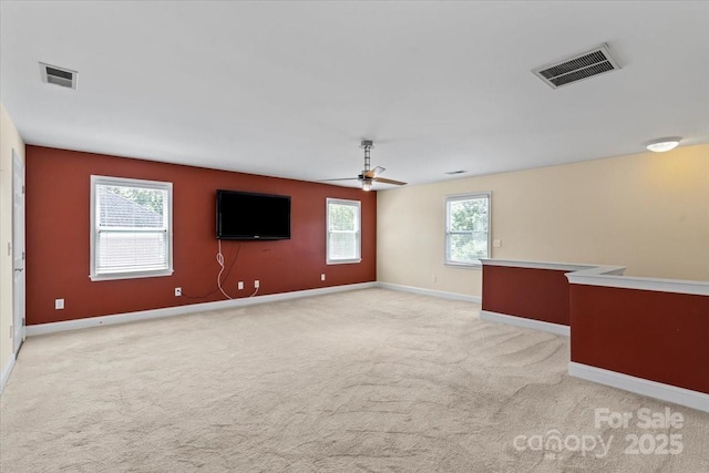 empty room with light colored carpet, a ceiling fan, and baseboards