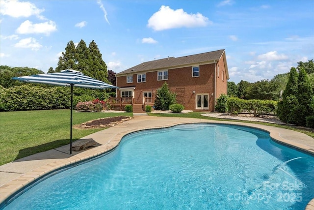 outdoor pool with a wooden deck and a yard