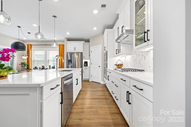12705 Twilight Dr, Mint Hill, NC 28227 - kitchen featuring light wood-type flooring, white cabinets, tasteful backsplash, a sink, and appliances with stainless steel finishes