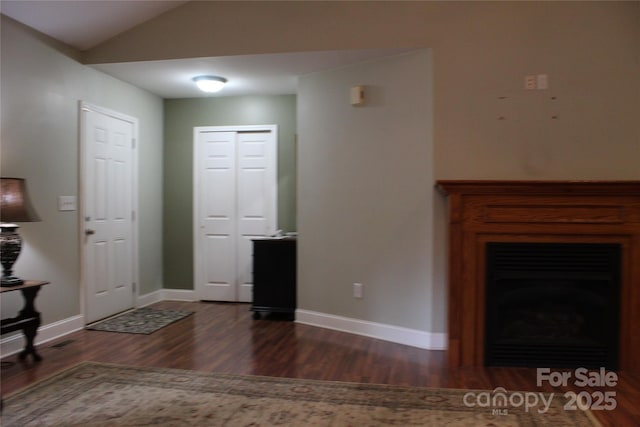 foyer featuring a fireplace, vaulted ceiling, wood finished floors, and baseboards