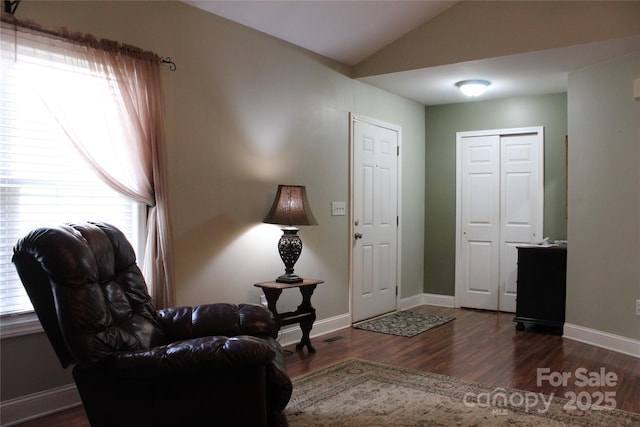 living area featuring vaulted ceiling, wood finished floors, a wealth of natural light, and baseboards