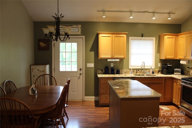 kitchen featuring wood finished floors, a sink, a chandelier, stainless steel range with gas stovetop, and a kitchen island