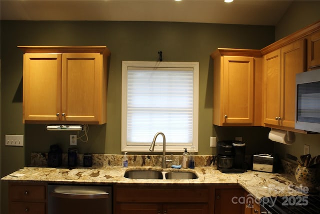 kitchen featuring recessed lighting, appliances with stainless steel finishes, light stone counters, and a sink