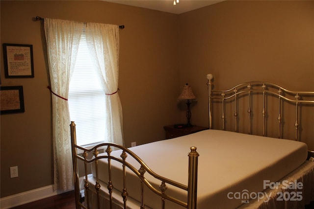 bedroom with baseboards and dark wood-type flooring