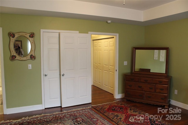 bedroom featuring baseboards, wood finished floors, and a closet