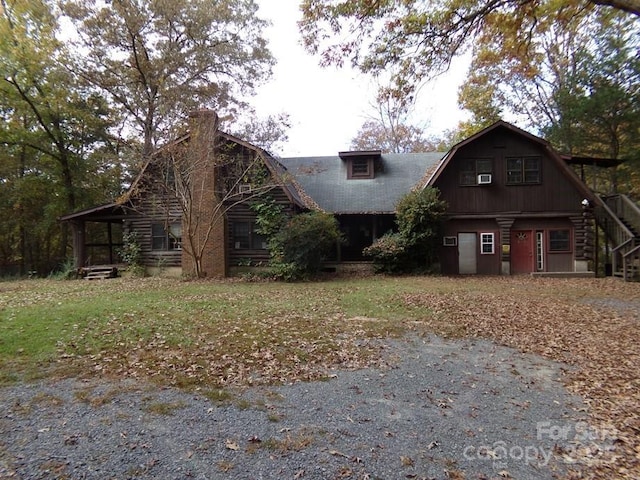 view of front facade featuring stairway, a gambrel roof, and a chimney