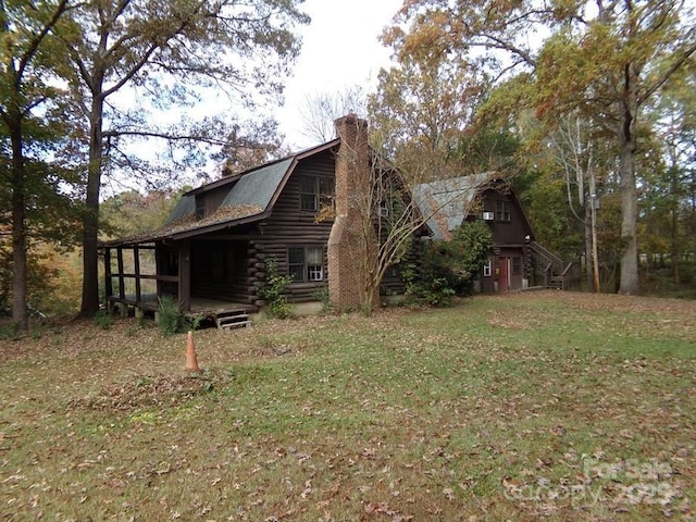 view of side of home featuring a chimney, a gambrel roof, log siding, and a lawn