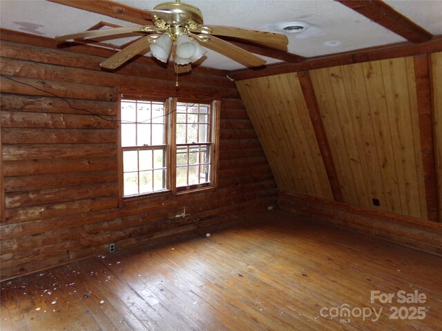 additional living space featuring ceiling fan, rustic walls, and hardwood / wood-style floors