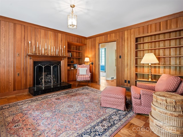 10 Stuyvesant Rd, Asheville, NC 28803 - living area with a fireplace with raised hearth, wooden walls, built in shelves, baseboards, and ornamental molding