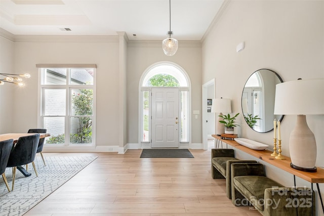 foyer with crown molding, baseboards, visible vents, and light wood-type flooring