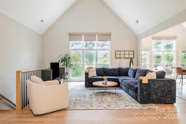 living area featuring high vaulted ceiling, visible vents, plenty of natural light, and wood finished floors