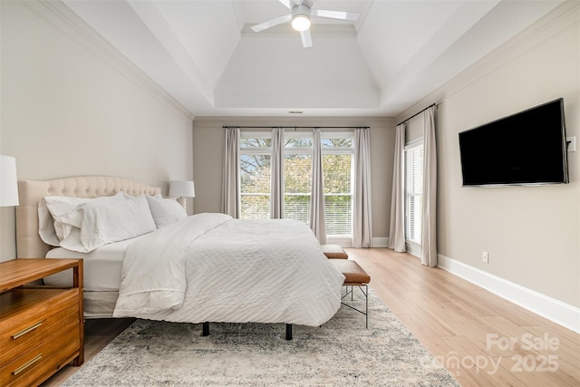 bedroom featuring lofted ceiling, baseboards, a tray ceiling, a ceiling fan, and light wood-style flooring