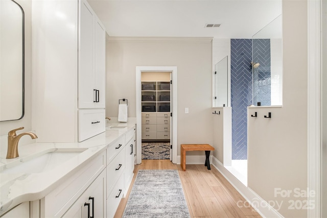 full bath with visible vents, a sink, a walk in shower, and wood finished floors