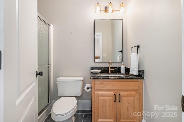full bathroom featuring baseboards, a stall shower, toilet, and vanity