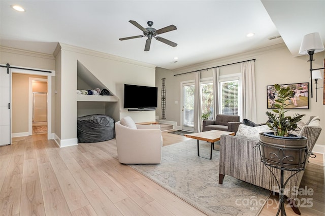 living room with baseboards, ornamental molding, a barn door, and wood finished floors