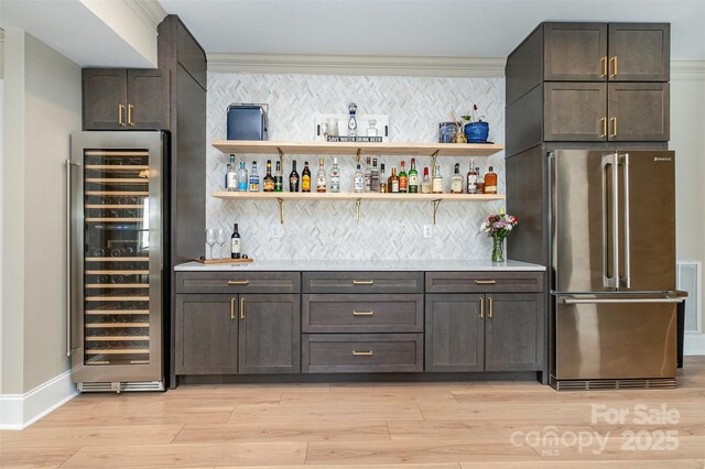 bar with a bar, freestanding refrigerator, light wood-style floors, and wine cooler