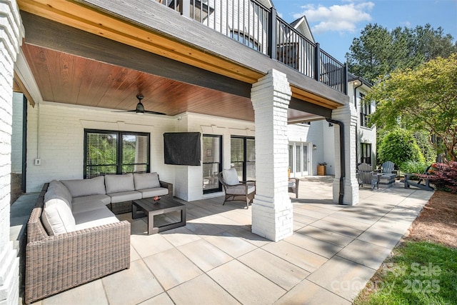 view of patio featuring an outdoor living space with a fire pit, a ceiling fan, and a balcony