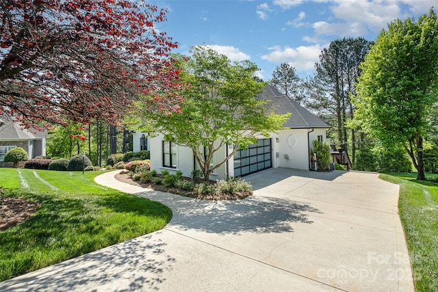 view of side of home with an attached garage, stucco siding, a yard, and concrete driveway