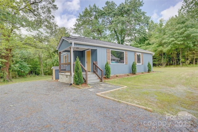 bungalow-style home with a porch, roof with shingles, driveway, and a front yard