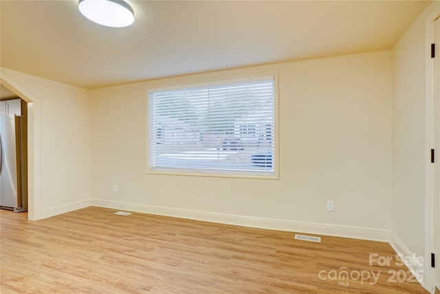 spare room with light wood-style floors, baseboards, and visible vents