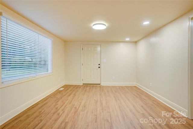 unfurnished room with light wood-type flooring, recessed lighting, and baseboards
